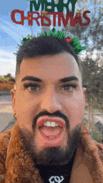 a man with a beard is wearing a merry christmas sign on his head