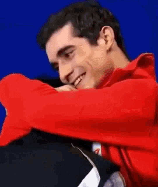 a man in a red jacket is smiling and hugging someone