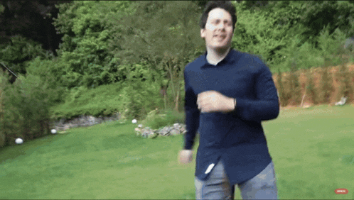 a man in a blue shirt is running across a grassy field