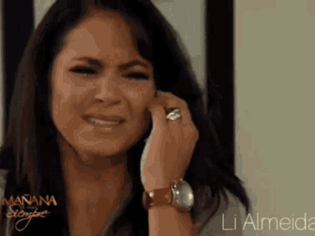 a woman is crying while talking on a cell phone with the name li almeida on the bottom