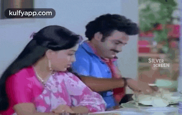 a man and a woman are sitting at a table eating .