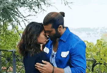 a man and a woman are kissing in a park .