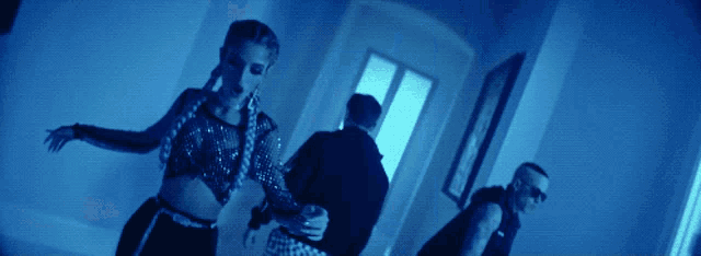 a woman in a crop top is dancing with two men