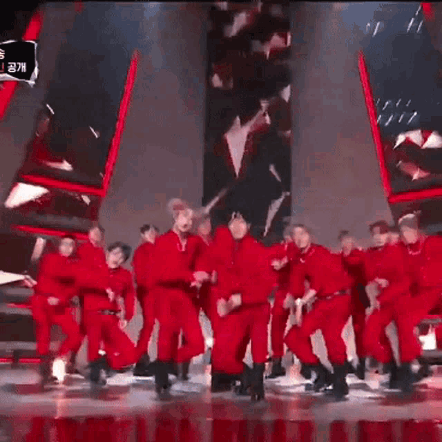 a group of people in red jumpsuits are dancing on stage