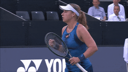 a woman holding a tennis racquet with a yonex logo in the background
