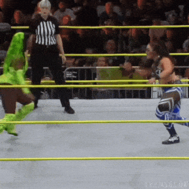 two women are wrestling in a ring with a referee in the background