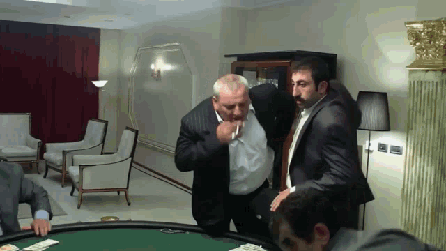 a man in a suit is smoking a cigarette while another man looks on
