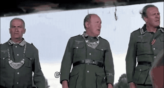 three men in military uniforms standing next to each other with a g on the bottom left