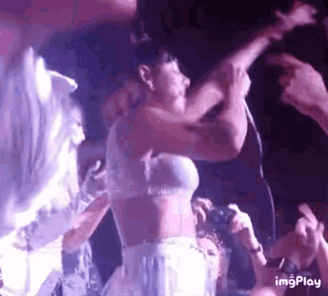 a woman in a white bra is singing into a microphone on a stage .