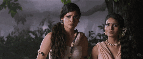 a couple of women standing next to each other with one wearing a necklace