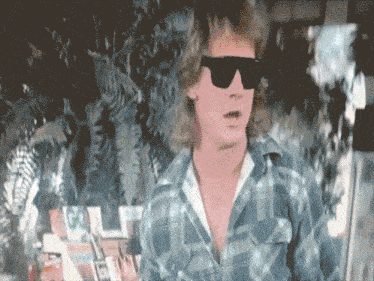 a man wearing sunglasses and a plaid shirt is standing in front of a magazine that says go
