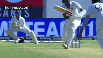 a cricket player is running on the field with a bat .