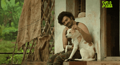 a man is sitting on a porch with a dog and a green xhk logo behind him