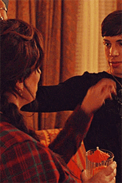 a woman in a plaid shirt is holding a glass with an orange umbrella on it