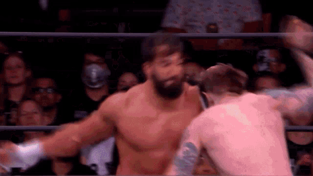 two men are fighting in a wrestling ring with a crowd watching .