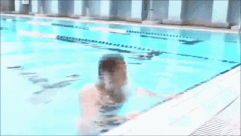 a man without a shirt is swimming in a pool with his mouth open
