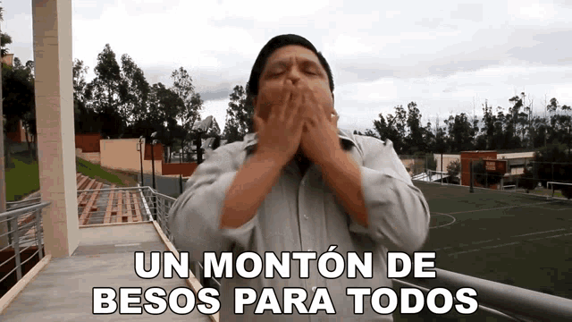 a man covering his mouth with his hands and the words " un monton de besos para todos " above him