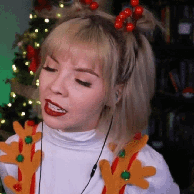 a woman wearing a reindeer headband with red berries