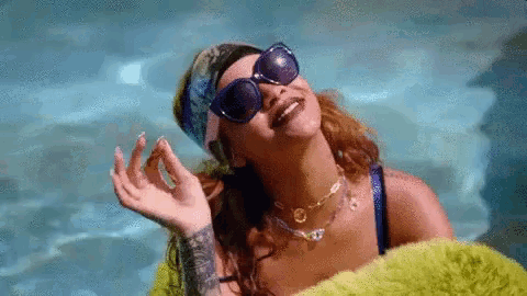 a woman wearing sunglasses and a bandana is laying in a pool .