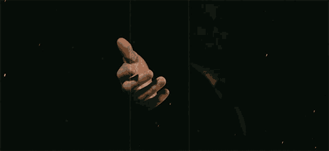 a man in a suit and tie is pointing his finger in the dark