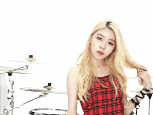 a woman in a red plaid top holds a drum stick