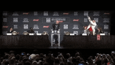 two men are standing in front of a podium with the number 205 on it .