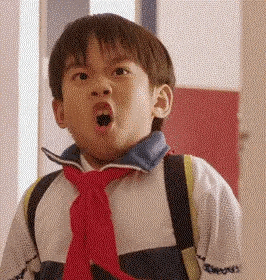 a young boy wearing a red tie and making a funny face .