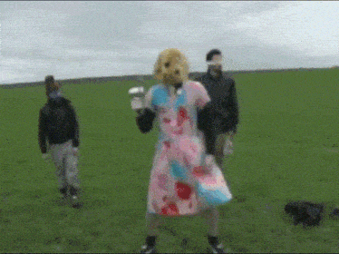 a woman in a pink and blue dress with a dog mask on her head