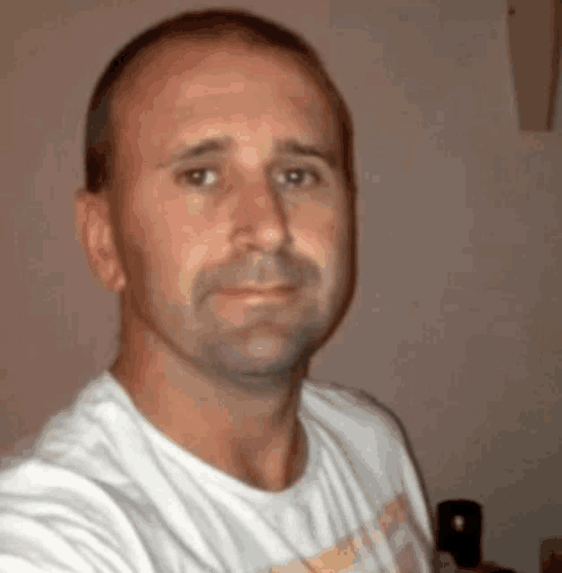 a man is wearing a white shirt and looking at the camera