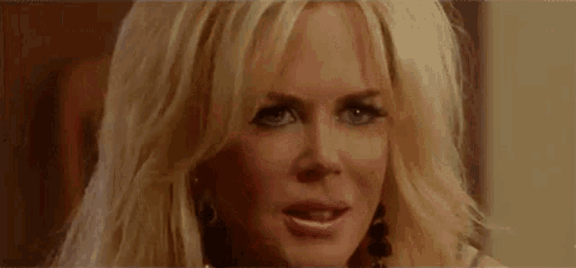 a close up of a blonde woman with blue eyes making a funny face .