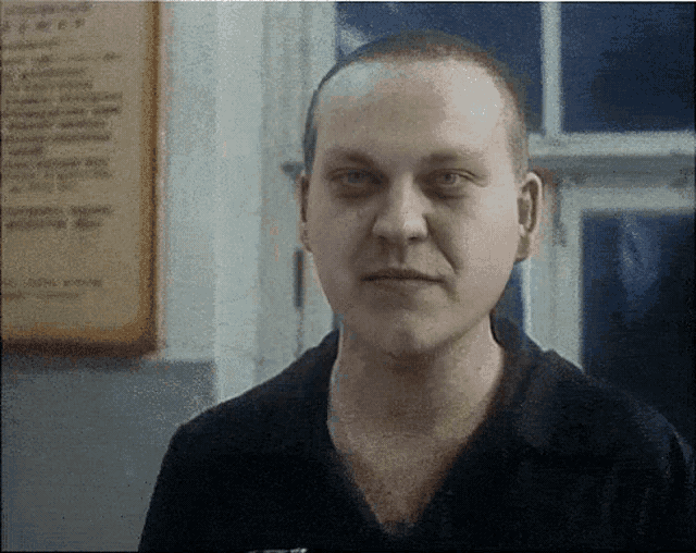 a man with a shaved head looks at the camera in front of a sign that says ' soviet union ' on it