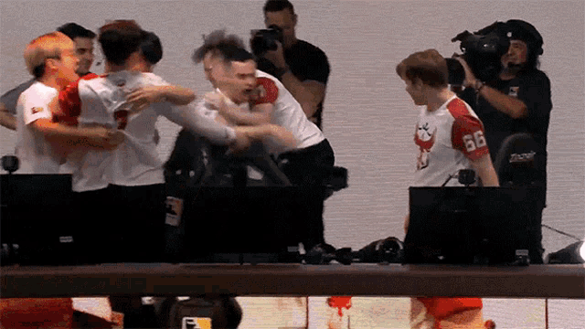 a group of people are hugging each other and one has the number 66 on his shirt