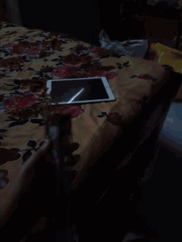 a person is holding a bottle and a tablet on a bed