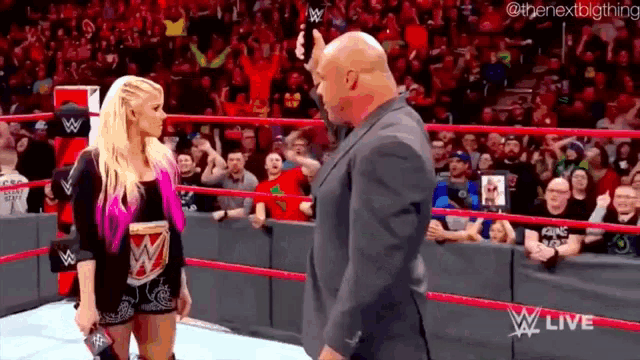 a man in a suit and a woman in a wrestling ring are standing next to each other .