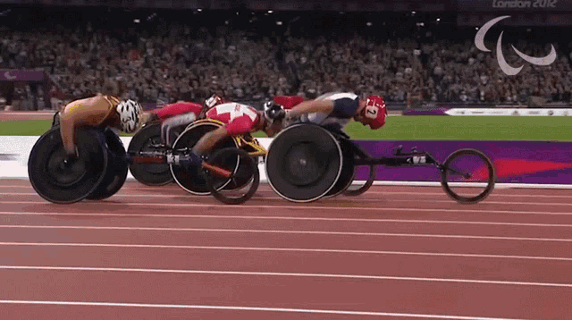 three wheelchair racers are racing on a track that says london 2012 on it