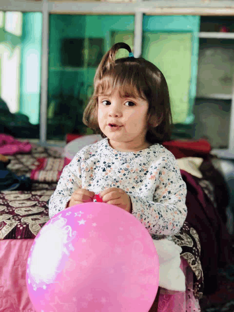 a little girl is holding a pink balloon that says " i love you "