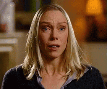 a woman with blonde hair and blue eyes is making a funny face with her mouth open .