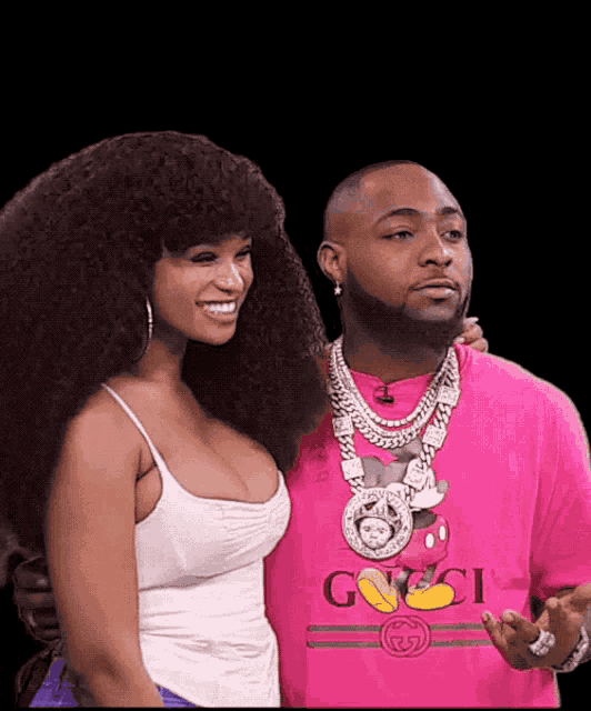 a man wearing a pink shirt that says gucci stands next to a woman