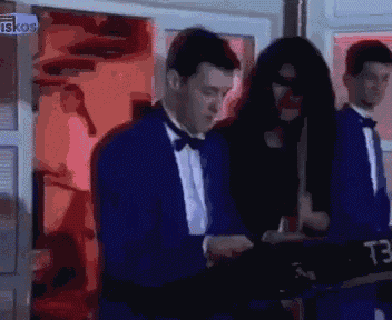 a man in a tuxedo stands next to a woman in a mask