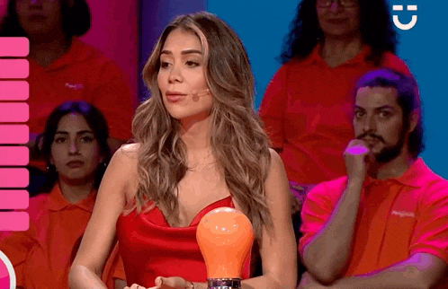 a woman in a red dress holds an orange light bulb in front of a crowd