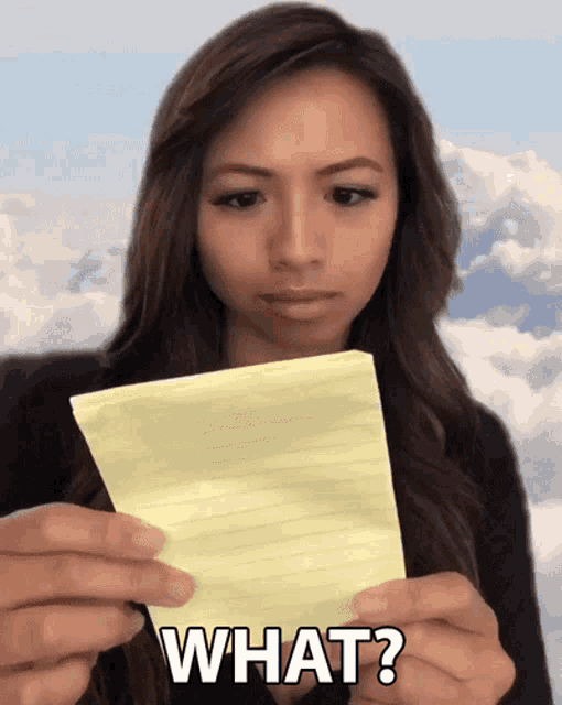 a woman is holding a piece of paper with the word what on it