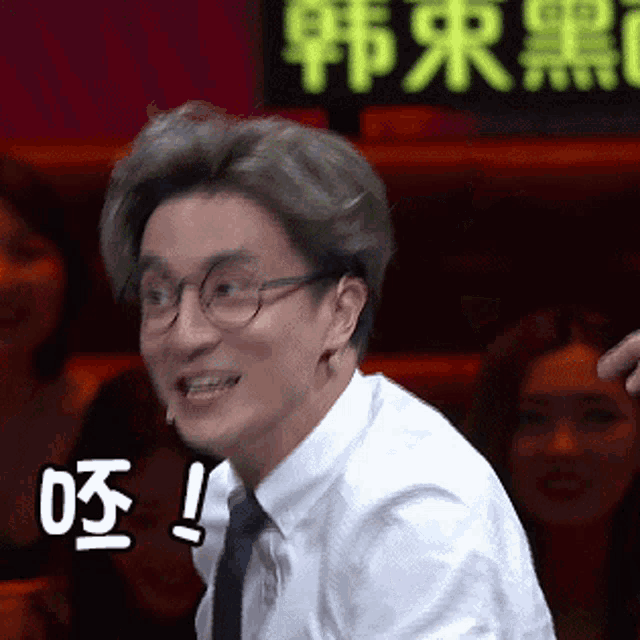 a man wearing glasses and a white shirt is smiling and making a funny face .