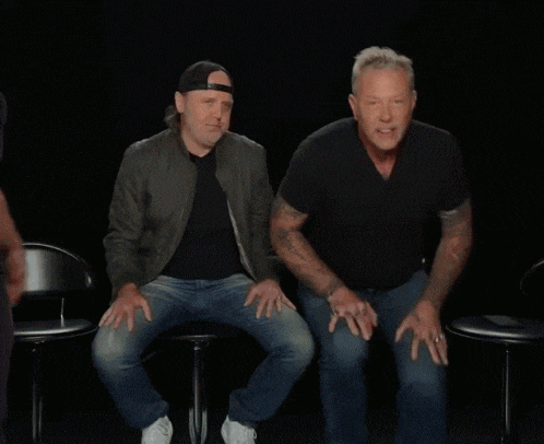 a man in a black shirt is giving the middle finger to another man