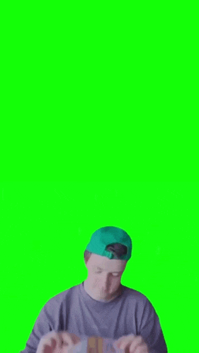 a man in a blue hat is holding a piece of paper in front of a green background .