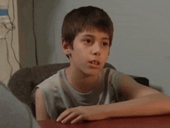 a young boy is sitting at a table with his hands on his hips