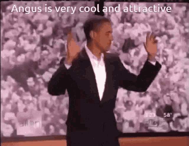 a man in a suit is dancing in front of a crowd with the words angus is very cool and attractive