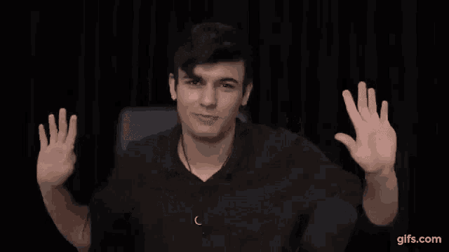 a man in a black shirt is waving his hands in the air .