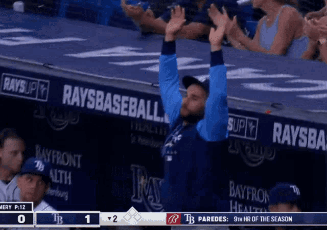 a man stands in front of a rays baseball banner