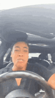 a woman is sitting in the driver 's seat of a car with her eyes closed .