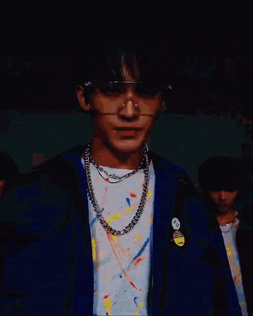 a young man with blue hair is wearing glasses and a chain around his neck